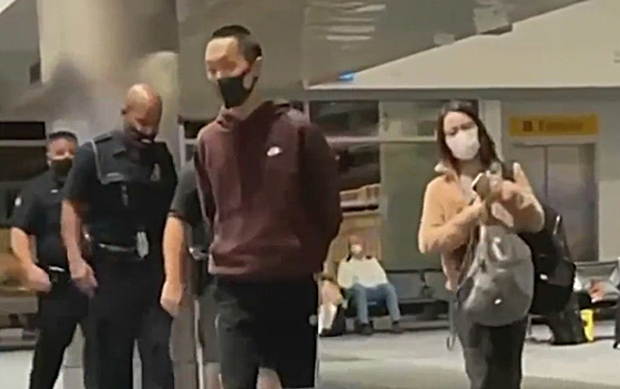  마스크 착용을 거부하며 비행기에서 난동을 부린 아시안계 남성이 덴버공항에서 경찰관들에게 연행되고 있다. [ABC7 캡처] 