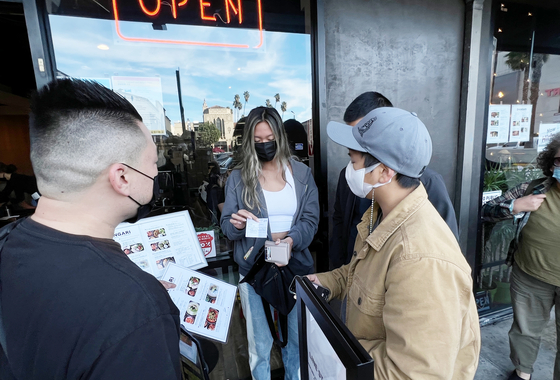 LA시가 오늘(29일)부터 실내업종 백신 접종 증명 의무화 시행 단속에 나선다. 지난 26일 LA한인타운 ‘항아리칼국수’ 앞에서 한 여성 손님이 직원에게 백신 카드를 보여주고 있다. 김상진 기자