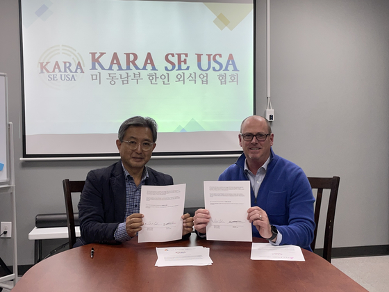 2021년 12월 21일 오후 노크로스에 있는 외식업협회 사무실에서 김종훈(왼쪽) 회장과 로버트 W. 베일스 회장이 공동구매 거래를 위한 계약서에 서명한 뒤 사진을 찍었다. 