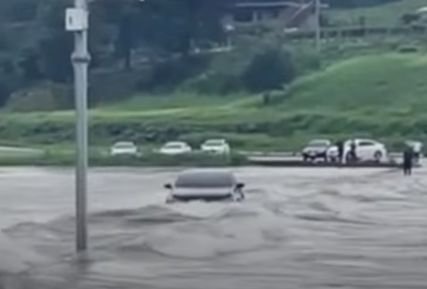 영월 남면 북쌍교를 건너던 차량이 강물에 휩쓸려 떠내려갔다. 오른쪽 끝 검은색 옷을 입은 사람이 운전자다. 사진 유튜브 캡처