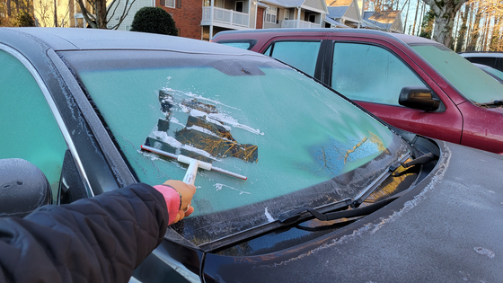 지난 4일 아침 둘루스의 아파트에서 한 한인이 밤새 얼어붙은 자동차 앞 유리창을 긁개로 긁어내고 있다. 