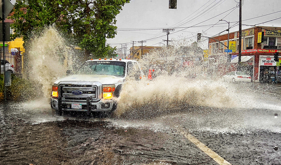 28일 LA일대에 쏟아진 폭우로 LA힌인타운 도로가 침수됐다. 자동차들이 후버길과 7가 코너에 빗물이 불어나면서 생긴 물웅덩이를 위를 물보라를 일으키면서 지나고 있다. 이 지역은 정전으로 신호등마저 작동하지 않아 아찔한 순간이 발생하기도 했다. 김상진 기자
