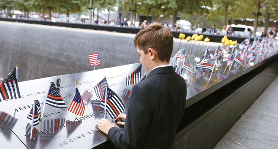 9·11 테러 21주년을 맞아 전국에서 다양한 추모 행사가 열렸다. 뉴욕 국립 9·11 기념관에서 한 소년이 성조기를 놓으며 희생자를 추모하고 있다. [로이터]