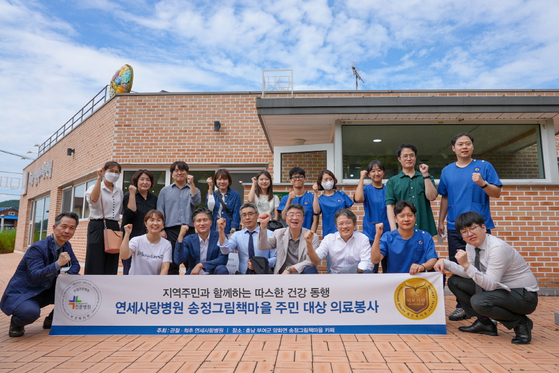 [연세사랑병원 의료진과 임직원이 송정그림책마을 의료봉사를 마치고 환하게 웃고 있다]