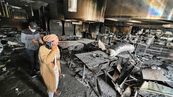 춘천닭갈비 업주와 직원이 화재로 전소된 식당 내부를 둘러보며 지인들과 통화하고 있다. 김상진 기자