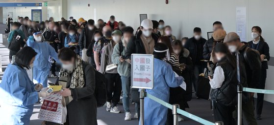지난 2일 인천국제공항 제1여객터미널 입국장에서 공항 관계자들이 중국발 입국자를 분류하고 있다.   방역당국은 이날부터 중국에서 항공편이나 배편으로 입국하는 모든 사람에 대해 코로나19 유전자증폭(PCR) 검사를 실시하는 등 고강도 방역 대책을 시작했다. 뉴스1