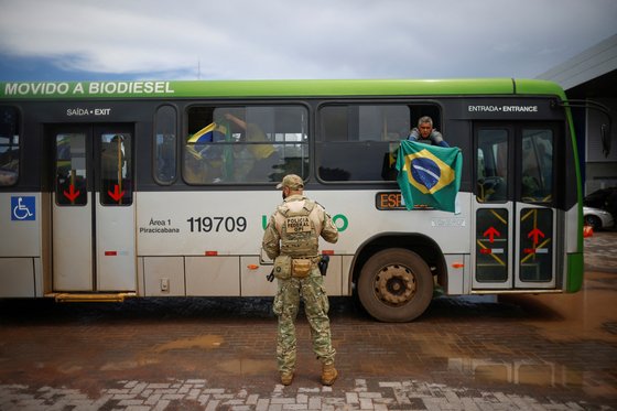 경찰에 검거된 보우소나루 전 대통령 지지자가 버스에서 깃발을 흔들고 있다. 로이터=연합뉴스