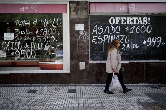 아르헨티나 부에노스아이레스에서 한 여성이 정육점 옆을 지나고 있다. 제품 가격이 하루가 다르게 올라 칠판이나 종이에 가격을 고쳐 적는 상점들이 많다. AP=연합뉴스 