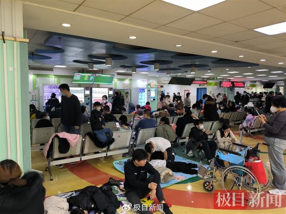 최근 폭증하는 어린이 폐렴 환자로 중국 각지의 병원이 심각한 포화상태에 빠졌다. 사진은 중국의 한 병원 접수대 앞 의자와 바닥에서 대기 중인 어린이 환자와 보호자. 중국 극목신문