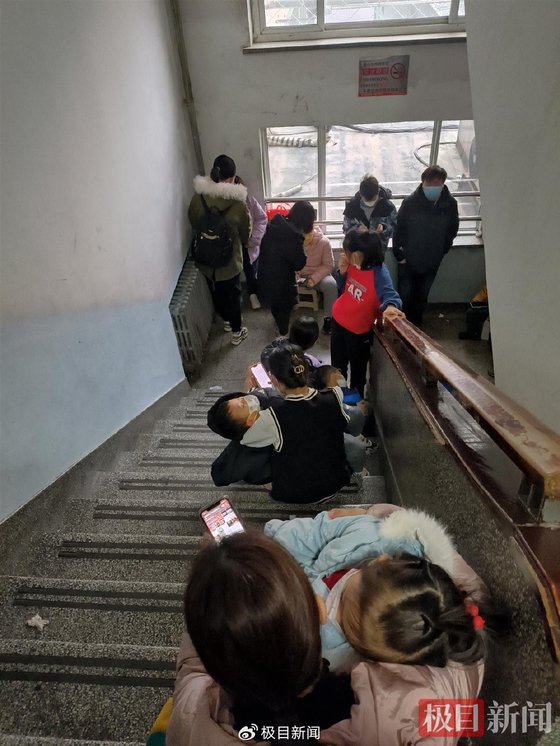 최근 폭증하는 어린이 폐렴 환자로 중국 각지의 병원이 심각한 포화상태에 빠졌다. 사진은 중국의 한 병원의 복도에서 대기 중인 어린이 환자와 보호자. 중국 극목신문