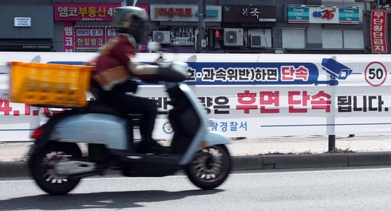 지난 3월 30일 오후 서울 중랑구 망우로 버스중앙차로에 설치된 후면 단속 안내 현수막 앞으로 오토바이가 지나가고 있다.  뉴스1