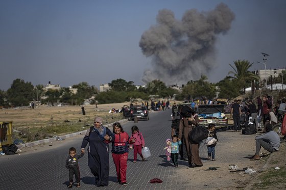 2일(현지시간) 팔레스타인 가자지구 남부도시 칸유니스 인근에서 이스라엘군 공습으로 인해 연기가 치솟는 가운데 팔레스타인 피난민들이 이동하고 있다.AP=연합뉴스
