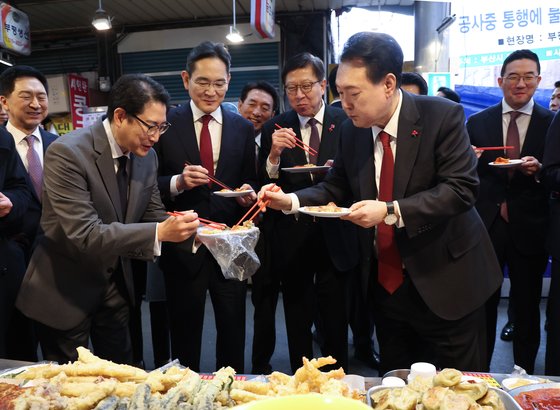 윤석열 대통령이 6일 부산 중구 깡통시장에서 재계 총수들과 분식을 맛보며 이재용 삼성전자 회장, 조현준 효성그룹 회장에게 빈대떡을 나눠주고 있다.  연합뉴스