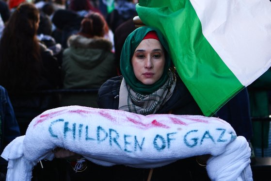 9일 영국 런던 중심부에서 열린 팔레스타인을 위한 전국 행진에 참석한 한 시위자가 가자지구 전쟁의 완전한 휴전을 촉구하며 "가자지구의 아이들"이라고 적힌 뭉치를 들고 있다. AFP=연합뉴스