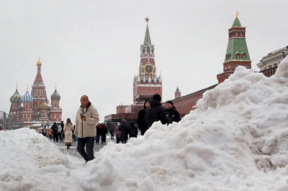 지난달 27일(현지시간) 모스크바에 폭설이 내린 후 크렘린궁 스파스카야 타워 앞 붉은 광장의 눈 언덕을 사람들이 지나가고 있다. EPA=연합뉴스