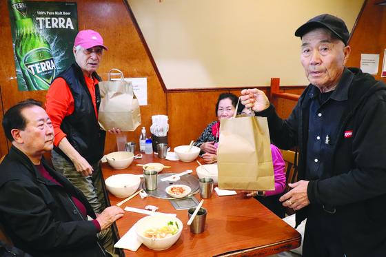 우태창 회장이 떡국 식사를 하는 참석자들에게 '떡 선물'을 전달하고 있다.
