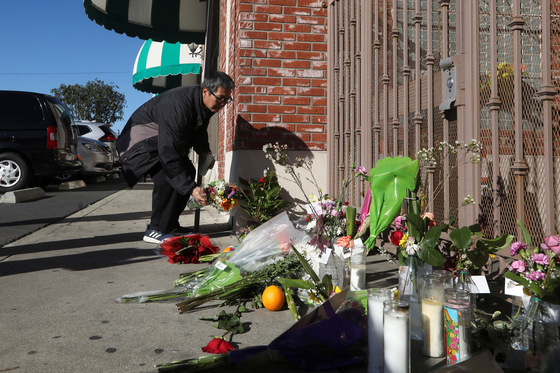 지난 21일 총기난사 사건이 벌어진 캘리포니아주 몬터레이파크 댄스 스튜디오 앞에서 23일 한 남성이 희생자들을 추모하며 꽃을 내려놓고 있다. [로이터] 