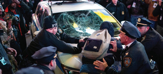 28일 맨해튼 타임스스퀘어에서 열린 테네시주 멤피스 경찰의 과잉 진압 규탄시위에서 참가자 중 한 명이 뉴욕시경 경찰차에 올라가 유리창을 깨 체포되고 있다.  [로이터]