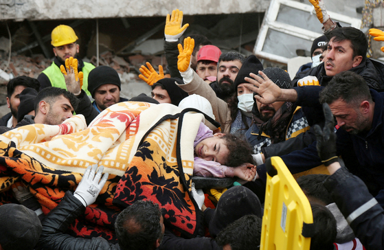 6일(현지시간) 대규모 강진이 발생한 튀르키예 남동부 이스켄데룬 지역의 붕괴한 병원 잔해에서 구조 요원들이 한 남성을 구조해 이송하고 있다. [로이터]