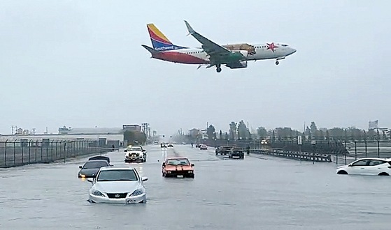 24일 할리우드 버뱅크 공항 인근 교차로가 폭우로 물에 잠기면서 지나던 차들이 침수된 상태로 방치돼 있다. [RawsAlerts 트위터]