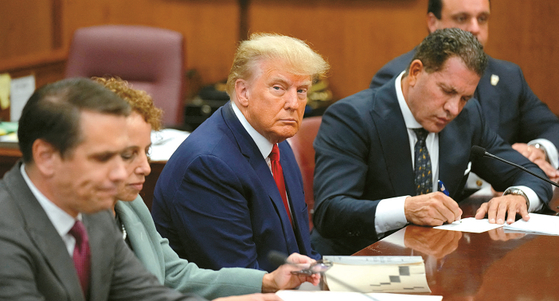 도널드 트럼프 전 대통령이 4일 맨해튼 형사법원에서 열린 기소인부 절차에 변호인들과 함께 참석해 앉아 있다. [로이터] 