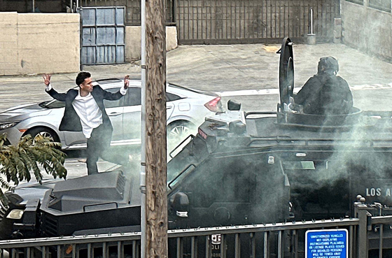 13일 LA한인타운 뱅크오브호프 올림픽-버몬트 지점 주차장의 차 안에서 경찰과 대치하던 은행 강도 용의자(왼쪽)가 경찰이 발사한 최루탄을 피해 손을 들고 차 밖으로 나오고 있다. 김상진 기자