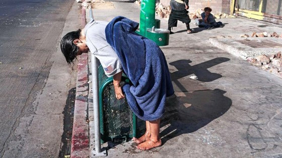 A mentally ill homeless woman leans on a rail after wetting her hair at a drinking fountain in the Skid Row area of Los Angeles, Monday, May 23, 2022. A controversial bill signed by Gov. Gavin Newsom could improve that by forcing people suffering from severe mental illness into treatment. But they need to be diagnosed with a certain disorder such as schizophrenia and addiction alone doesn't qualify. (AP Photo/Jae C. Hong)