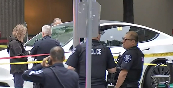 13일 한인 임신부가 총에 맞아 사망한 시애틀에서 경찰관들이 총격을 받은 테슬라 주변을 통제하고 조사를 벌이고 있다. 차량 운전석 창문에 총알 구멍이 선명하게 보인다. [KIRO 7 캡처]