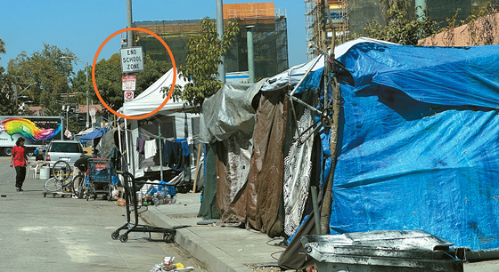 12일 버질 중학교 인근 노스 후아니타 애비뉴에 홈리스가 사는 10여 개의 텐트가 인도를 점령하고 있다. 사진 왼쪽 주황색 원 안에 스쿨존 표지판이 있지만 지속적인 효과를 내는 단속은 이뤄지지 않고 있다. 김상진 기자