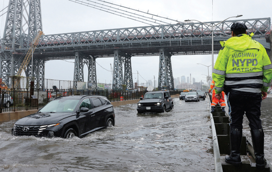 29일 뉴욕에 기록적인 폭우가 내린 가운데 뉴욕시경(NYPD) 경찰관이 맨해튼 윌리엄스버그 브리지 인근 FDR드라이브에서 침수된 거리 위를 운전하는 차들을 바라보고 있다. [로이터]