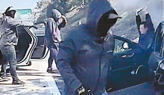 강도 용의자들이 고의로 교통사고를 낸 뒤 손을 들고 있는 피해자(오른쪽) 차량에서 금품을 강탈하고 있다. [fox11 캡처]