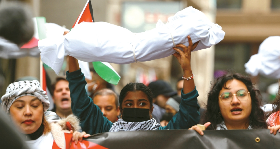 17일 보스턴에서 열린 가자지구 평화 보장 시위에서 팔레스타인계 여성이 이스라엘과 하마스간 전쟁으로 가자지구내 숨진 아동들을 상징하는 흰천에 싸인 마네킹을 들어올리고 있다.  [로이터]