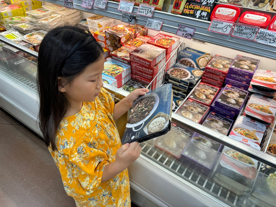 가족과 함께 트레이더조 매장에 방문한 아이가 한식 제품에 관심을 갖고 자세히 보고 있다.