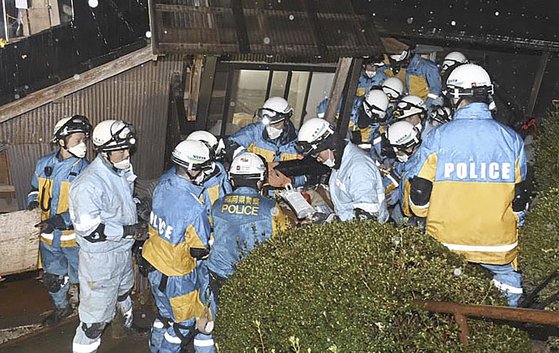 6일 저녁 일본 이시카와현 스즈시의 한 무너진 가옥에서 90대 여성이 경찰구조대에 의해 구조되고 있다. 지진 발생으로부터 124시간이 지났지만 여성은 구조대원의 질문에 대답을 할 정도로 건강한 것으로 나타났다. AP=연합뉴스 
