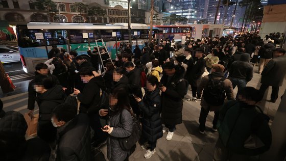 지난 5일 저녁 서울 중구 명동에서 퇴근길 시민들이 버스를 기다리고 있다.   서울시는 명동입구 광역버스 정류소에 노선 표시 안내판(줄서기 표지판)을 설치한 뒤 오히려 퇴근길 차량 정체가 심해지자 표지판 운영을 이달 31일까지 유예하기로 했다. 연합뉴스
