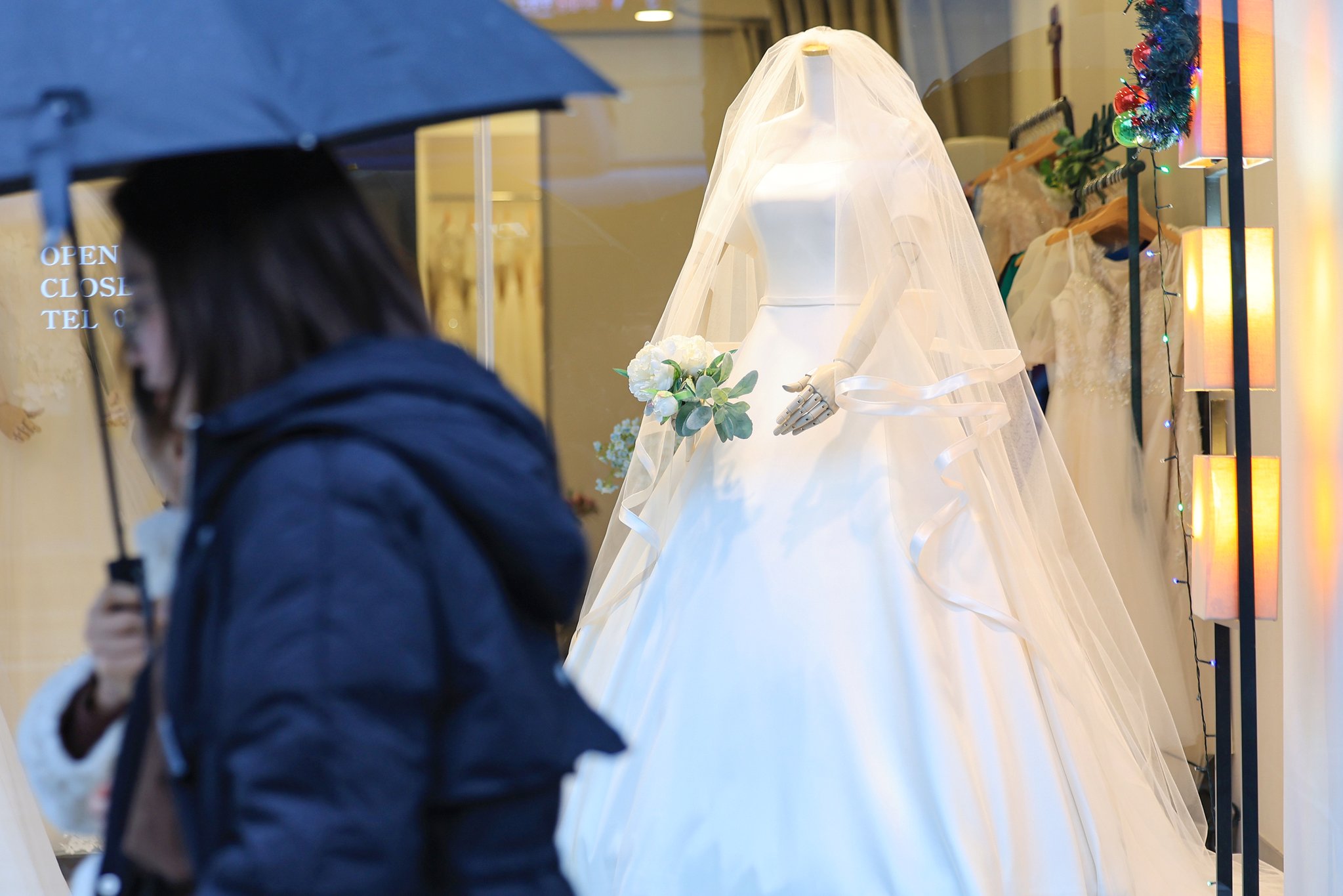 지난달 서울 마포구 아현동 웨딩거리의 한 웨딩드레스 판매점 앞을 시민들이 지나가고 있다.   연합뉴스