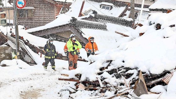 8일 일본 이시카와현 스즈시에서 눈이 오는 가운데 구조대원들이 피해자 구조 작업을 하고 있다. AFP=연합뉴스 
