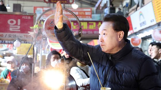 윤석열 대통령이 25일 경기도 의정부시 의정부제일시장을 찾아 어묵을 먹으며 시민들에게 인사하고 있다. 연합뉴스