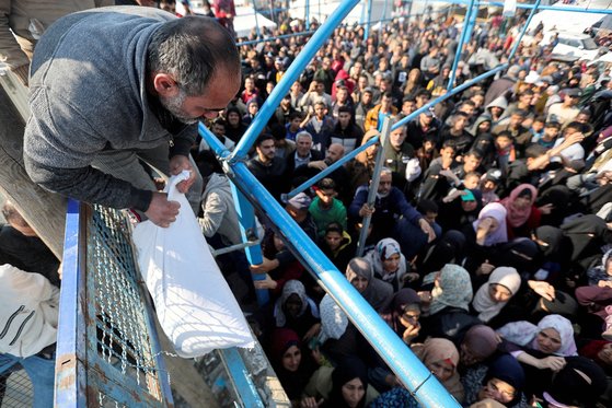 가자지구 남부 칸유니스에 있는 팔레스타인 사람들이 지난해 11월 29일 유엔 팔레스타인 난민구호기구(UNRWA)에서 제공하는 밀가루를 받기 위해 구호트럭에 몰려있다. 로이터=연합뉴스