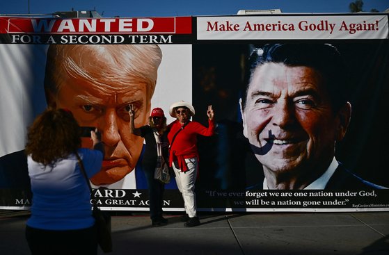 지난달 27일 미국 네바다주 라스베이거스에서 도널드 트럼프 전 대통령 지지자들이 트럼프와 로널드 레이건 전 대통령의 사진 앞에서 촬영을 하고 있다. AFP=연합뉴스