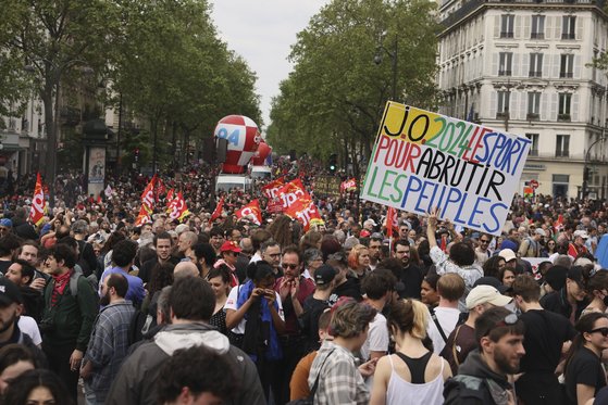 지난 1일 프랑스 파리에서 열린 노동절 시위에서 한 시위자가 파리올림픽을 반대하는 플래카드를 들고 있다. 노동자 수천명은 이날 올림픽 기간에 더 나은 임금과 근무 조건을 요구하는 시위를 벌였다. AP=연합뉴스