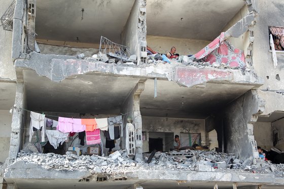 22일(현지시간) 가자지구 남부 라파에서 팔레스타인인들이 이스라엘의 공습으로 파괴된 집 안에 서 있다. 로이터=연합뉴스