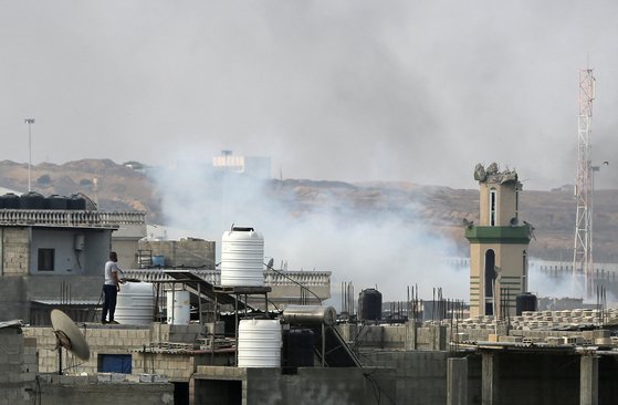한 남성이 28일 옥상 위에서 가자지구 라파 만단에서 연기가 피어오르는 곳을 지켜보고 있다. 로이터=연합뉴스\