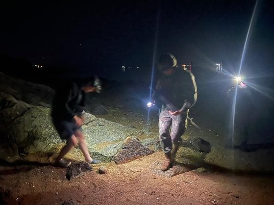 지난 29일 인천 영종도에서 실탄을 발견한 낚시객(왼쪽)과 군인이 바닥을 살피는 모습. 사진 온라인 커뮤니티