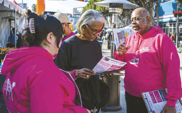 비영리단체 We Are LA의 봉사자들이 거리에서 주민들에게 퇴거 방지 지원 안내서를 나눠주고 있다.