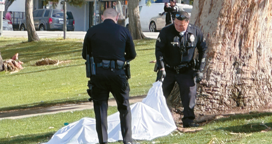 지난달 18일 경찰관들이 LA한인타운 인근 맥아더 파크에서 약물 과다로 사망한 한 남성의 시신을 살펴보고 있다. 김상진 기자