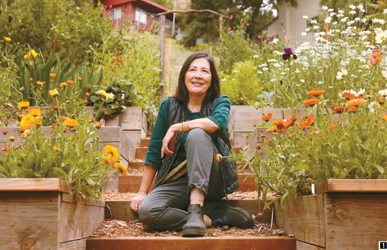 친구 집 뒤뜰을 일궈 꽃농장 사업을 하고 있는 캐서린 퍼거슨씨가 자신의 농장 '프로그타운 플로라' 계단에 앉아 웃고 있다.