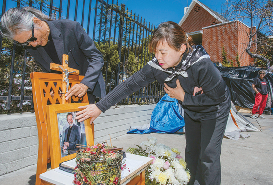 지난달 30일 김요한(왼쪽) 신부와 최광옥(오른쪽) 전도사가 고 이강원 목사가 숨진 장소에 영정사진과 꽃을 설치하고 있다. 김상진 기자