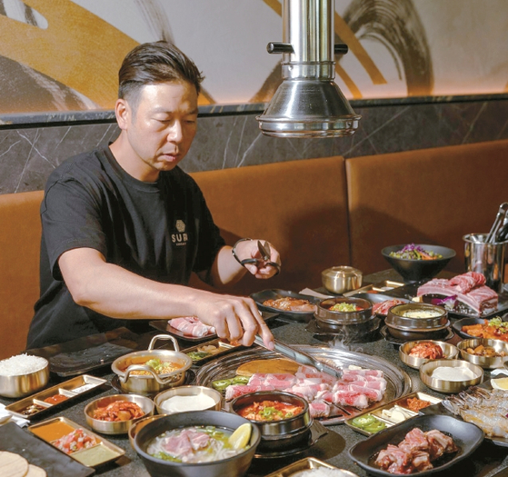 오타이메사에 새로 오픈한 '수라 Korean BBQ' 의 파트너 오너인 크리스 리앵 씨가 고기 서브 시범을 보이고 있다. [수라 제공]