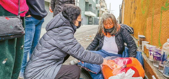 28일 세계등대교회(담임 김도일 목사) 관계자들이 본지에 소개된 한인 노숙자 윤애복씨를 찾아 침낭을 전달하고 있다.  김상진 기자